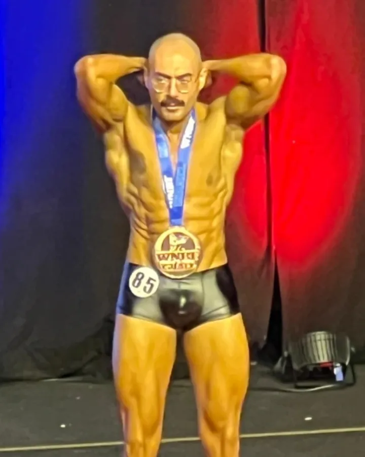 Michael Nektalov on stage at WNBF 2024, wearing his third-place medal